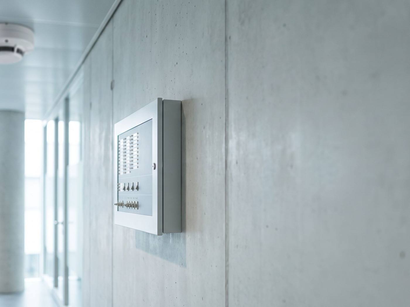 Un inspecteur teste un détecteur de fumée au plafond d'un hall industriel