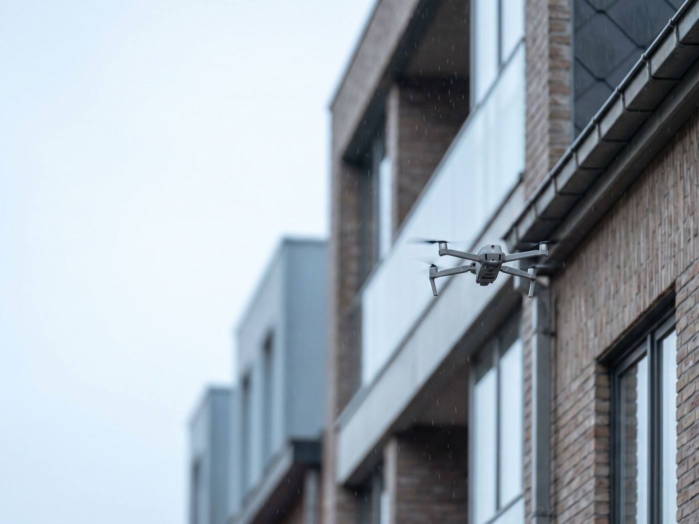 Un drone d'inspection en vol stationnaire près d'un détecteur de fumée sous la toiture d'un grand hall industriel