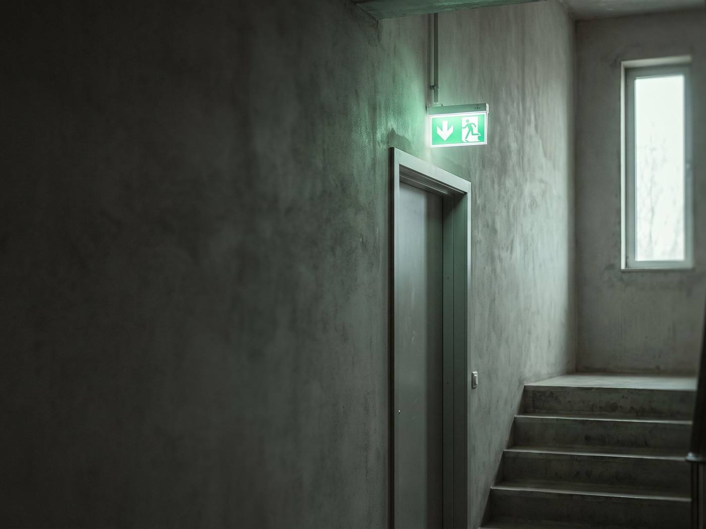 Un inspecteur mesure le niveau d'éclairement sous un luminaire de secours dans un couloir sombre